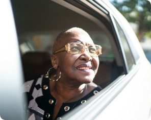 Lady in glasses looking out of the car, smiling